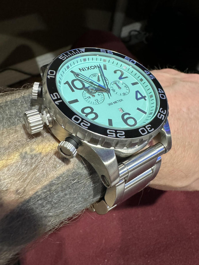 Close up image of the silver and turquoise Nixon 51-30 Chrono on a man's wrist in the sunlight