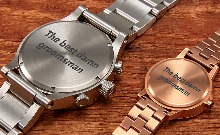 Two engraved watches, one silver and one rose gold, with "The best damn groomsman" on the back.