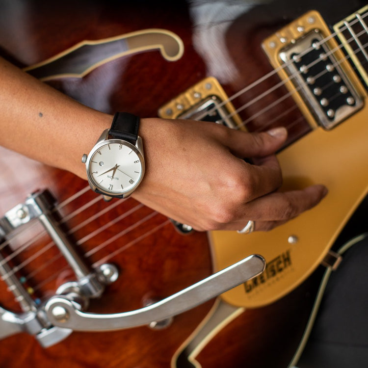 The Nixon Thalia leather watch on the wrist of a female guitar player.