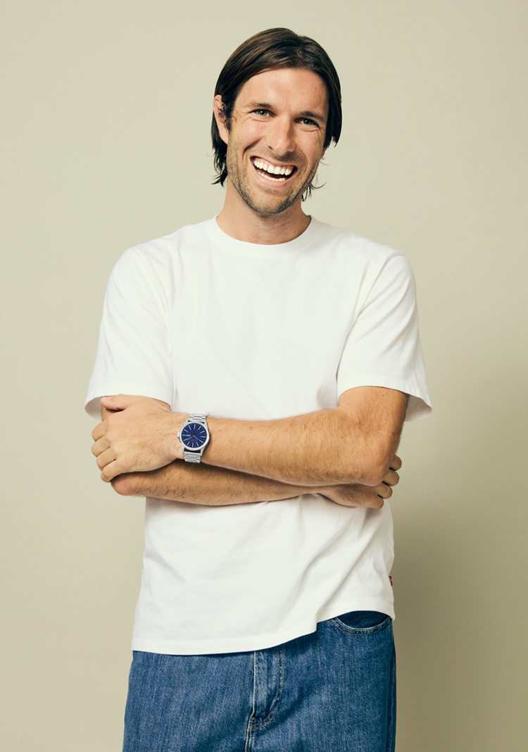 Man wearing a silver Nixon Sentry Stainless Steel with his arms crossed and smiling.