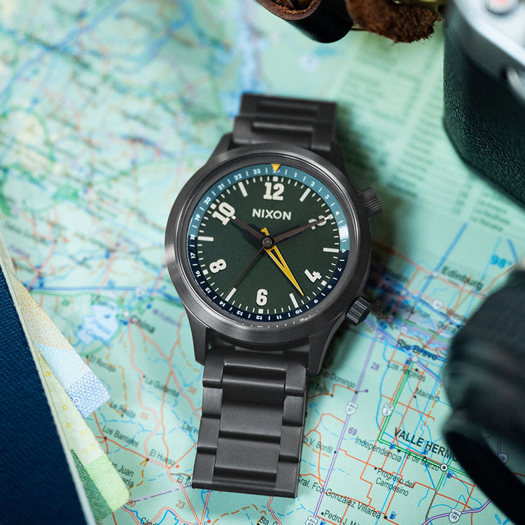 Nixon Drifter GMT watch sitting on a map for travel.