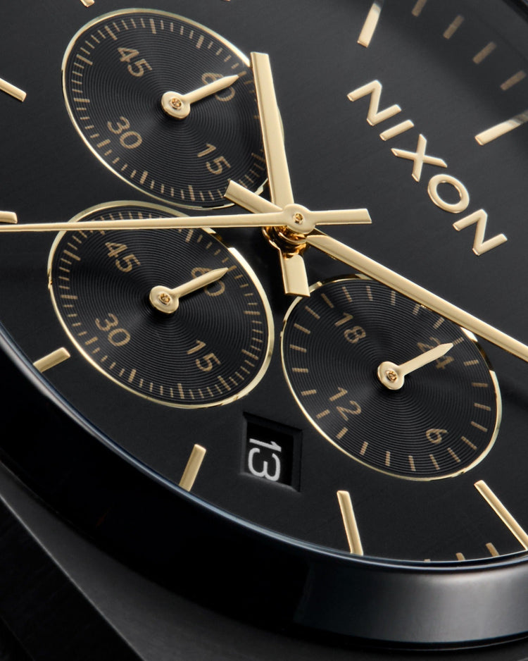 Close up of a dial on a Nixon analog chronograph watch in black and gold