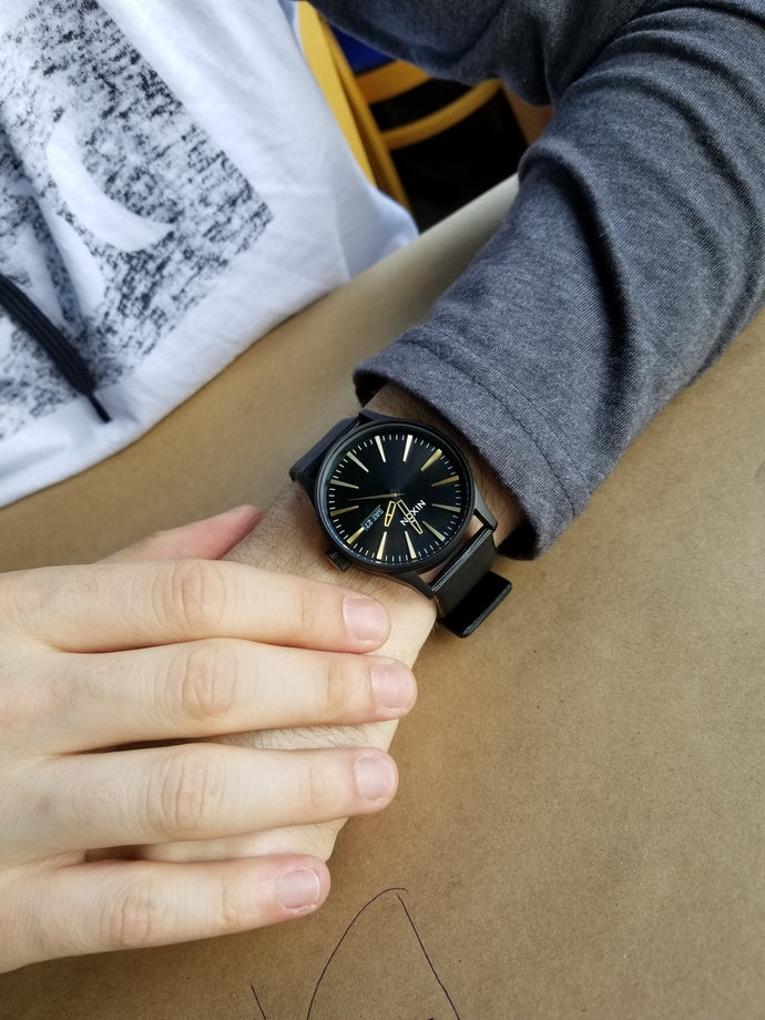 A black and gold Sentry Leather watch shown on a man's wrist