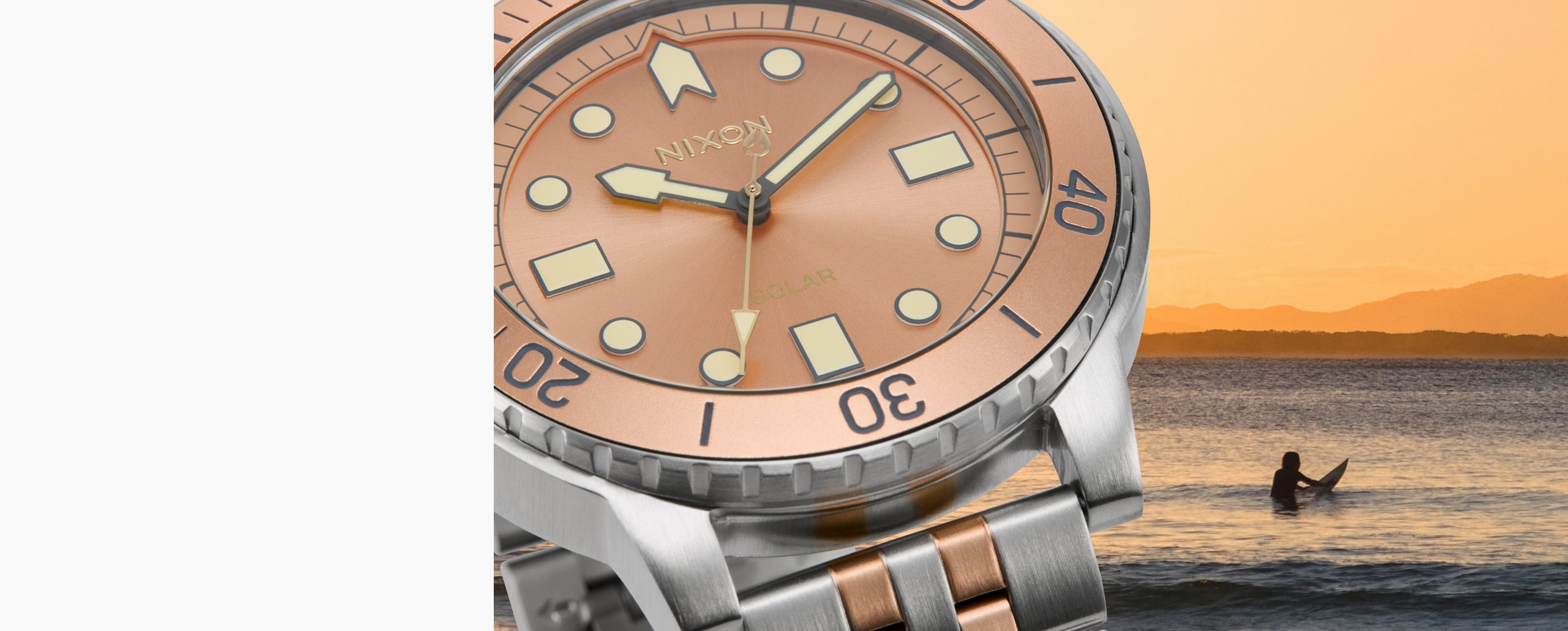 rose gold and silver watch over a ocean and surfer photo