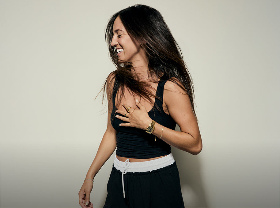 Woman laughs while wearing a gold Frankie watch from Nixon