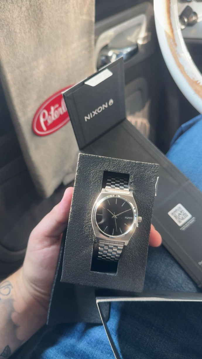 Person unboxing their new black Nixon Time Teller watch