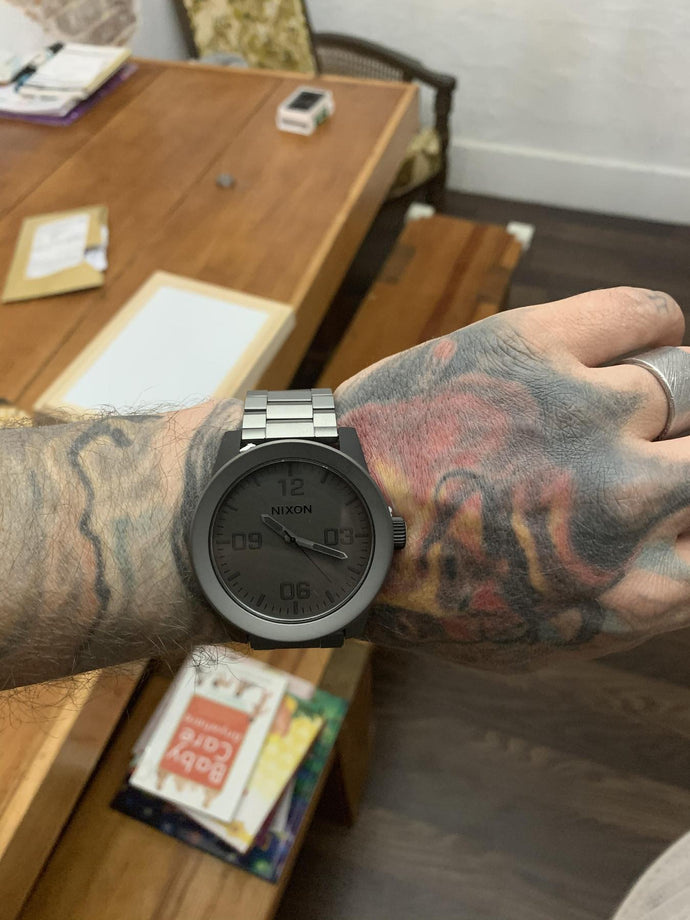 Man with a tattooed arm showing off his Corporal Stainless Steel in black