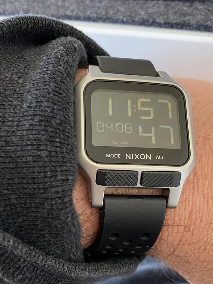 Man pulls up the sleeve of his sweater to show off his Nixon Heat digital watch.