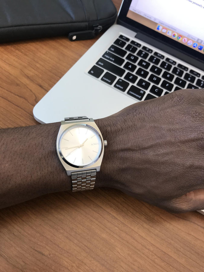 Person working on a laptop and wearing an All Silver Nixon Time Teller quartz watch
